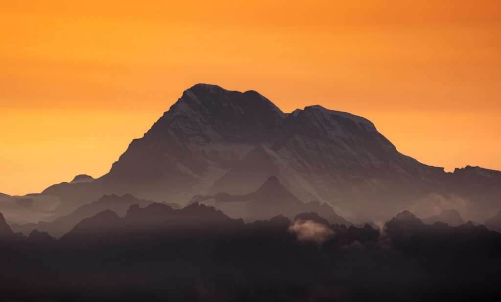 Majestic mountain silhouetted against an orange sky.